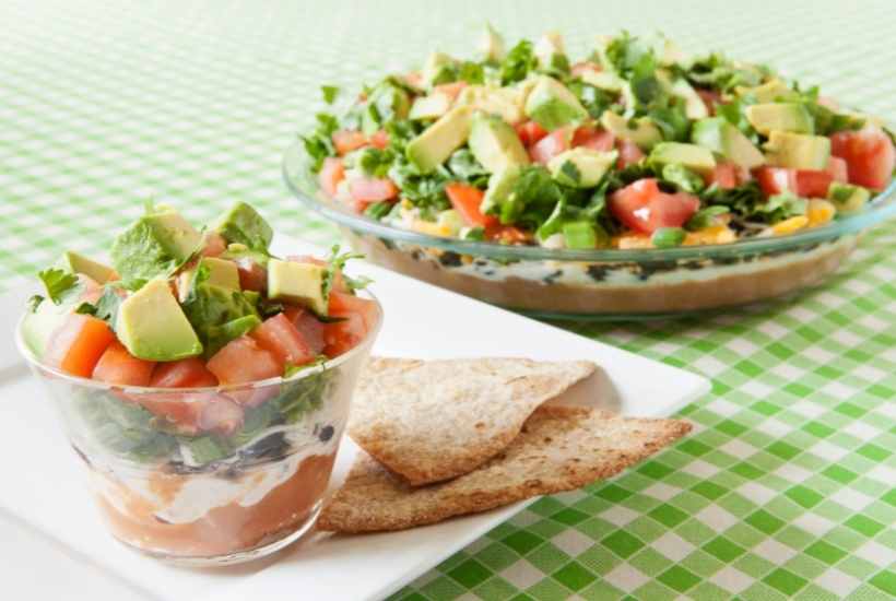 Seven layer taco dip with tortilla chips to serve at the party.