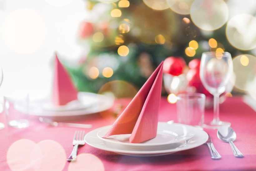 A table decorated for Christmas tea with Christmas tree in the background.