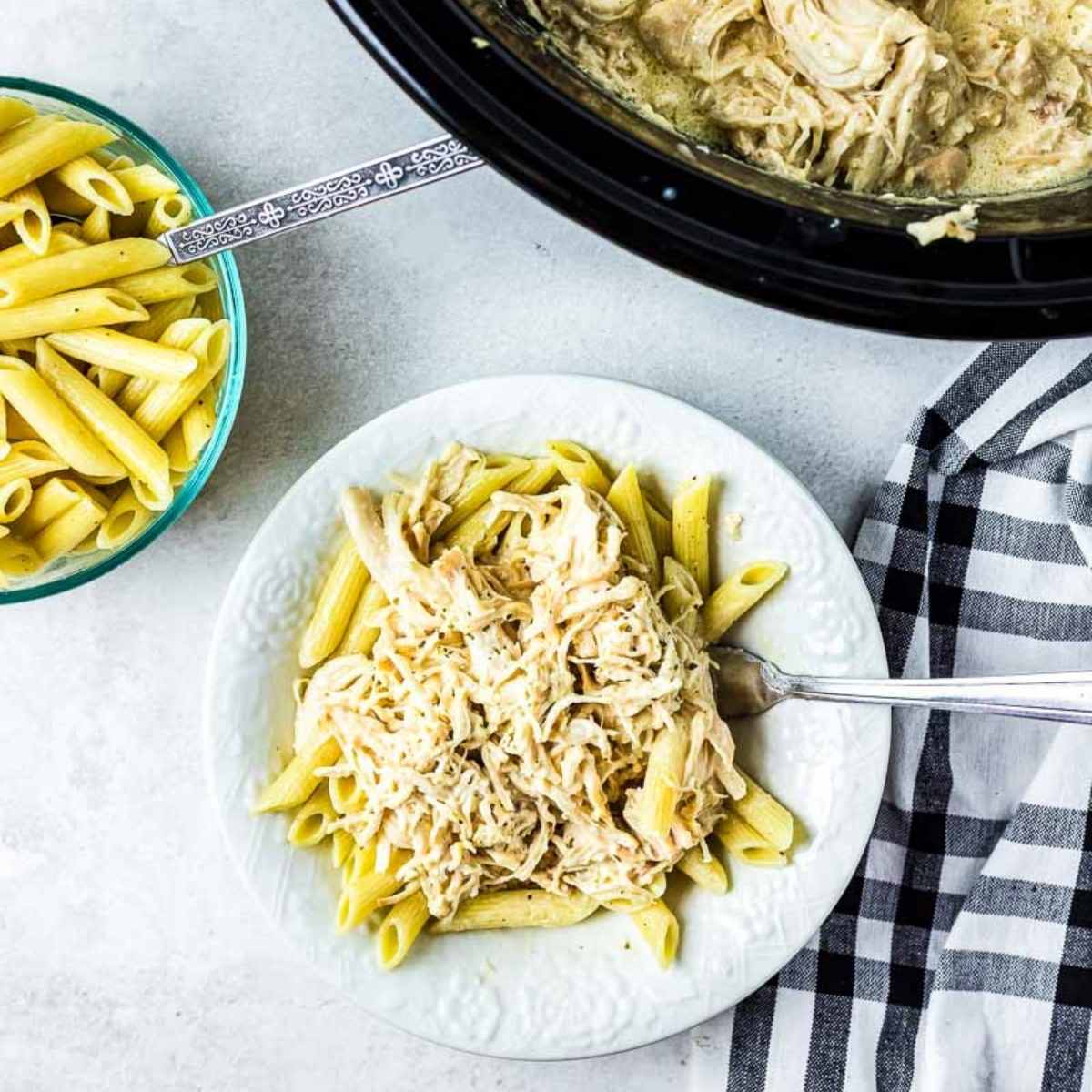 crockpot olive garden chicken shredded on top of a white plate with noodles