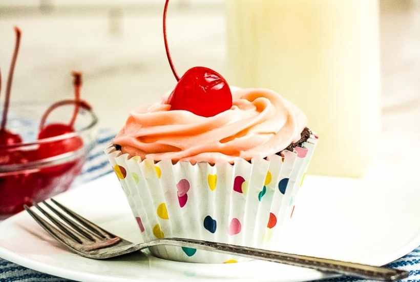 close up of a cherry chocolate dr pepper cupcake with a fork on a white plate