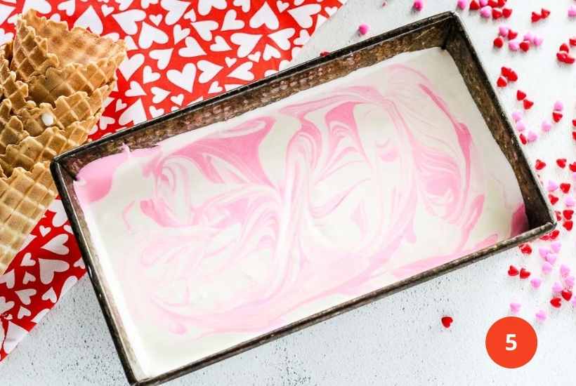 marbled cream mixture in a pan next to waffle cones