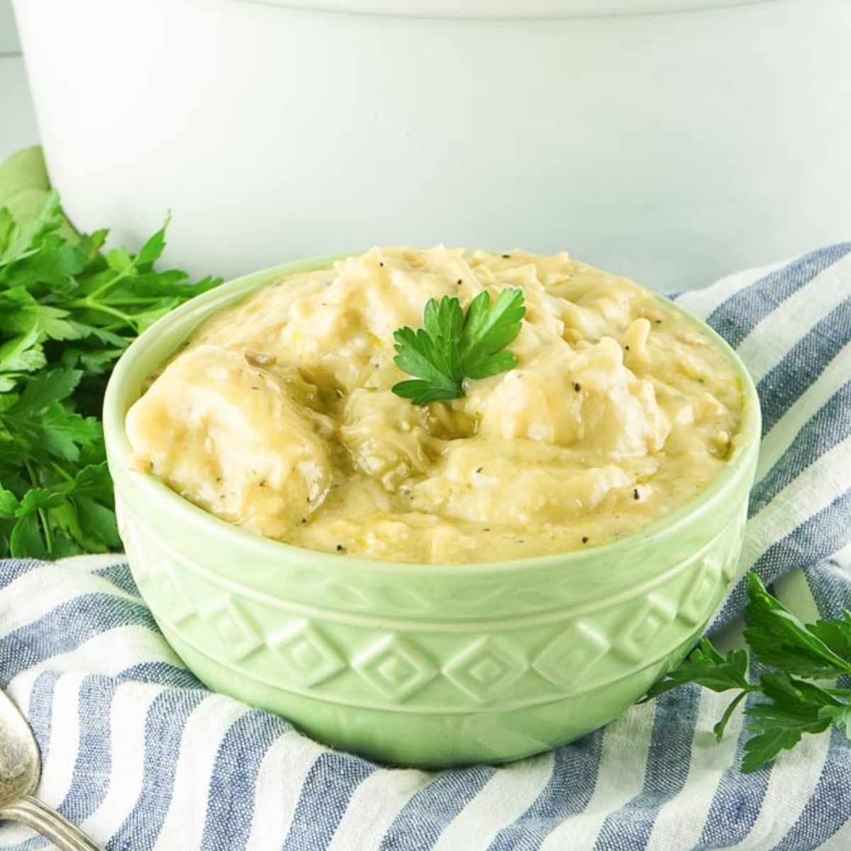 a green bowl filled with slow cooker chicken and dumplings made with biscuits