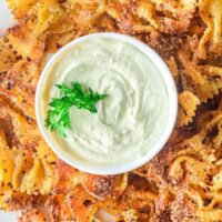 a bowl of whipped feta dip in the center of a plate of pasta chips