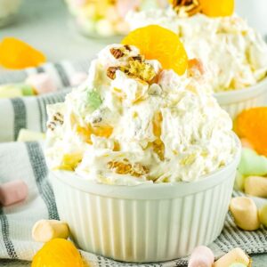 closeup of ambrosia salad with cool whip in a small ramekin next to marshmallows