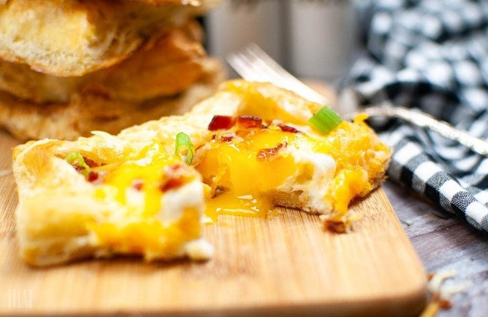 a puff pastry egg tart sliced in half with yolk running out onto a cutting board