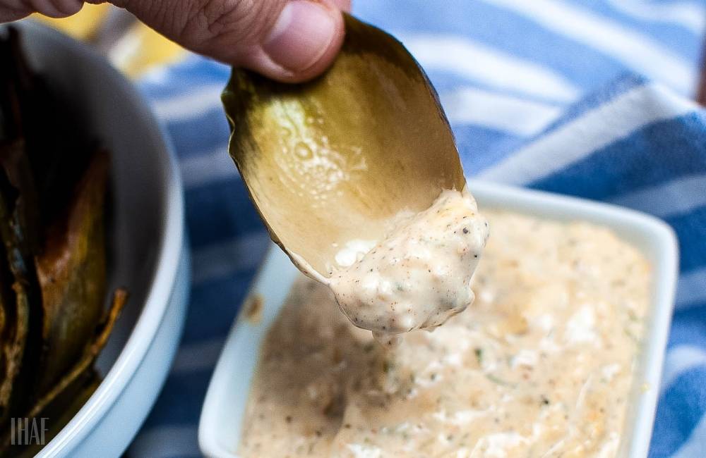 artichoke leaf being dipped in aioli sauce