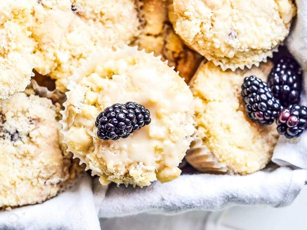 closeup of lemon blackberry muffins topped with homemade glaze and whole blackberries