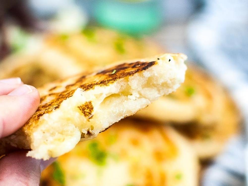 close up of Arepas Con Queso with a bite taken out of the arepa