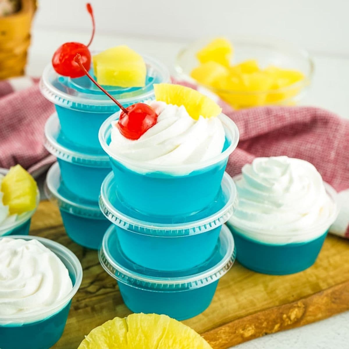 several blue hawaiian jello shots in plastic cups stacked on each other