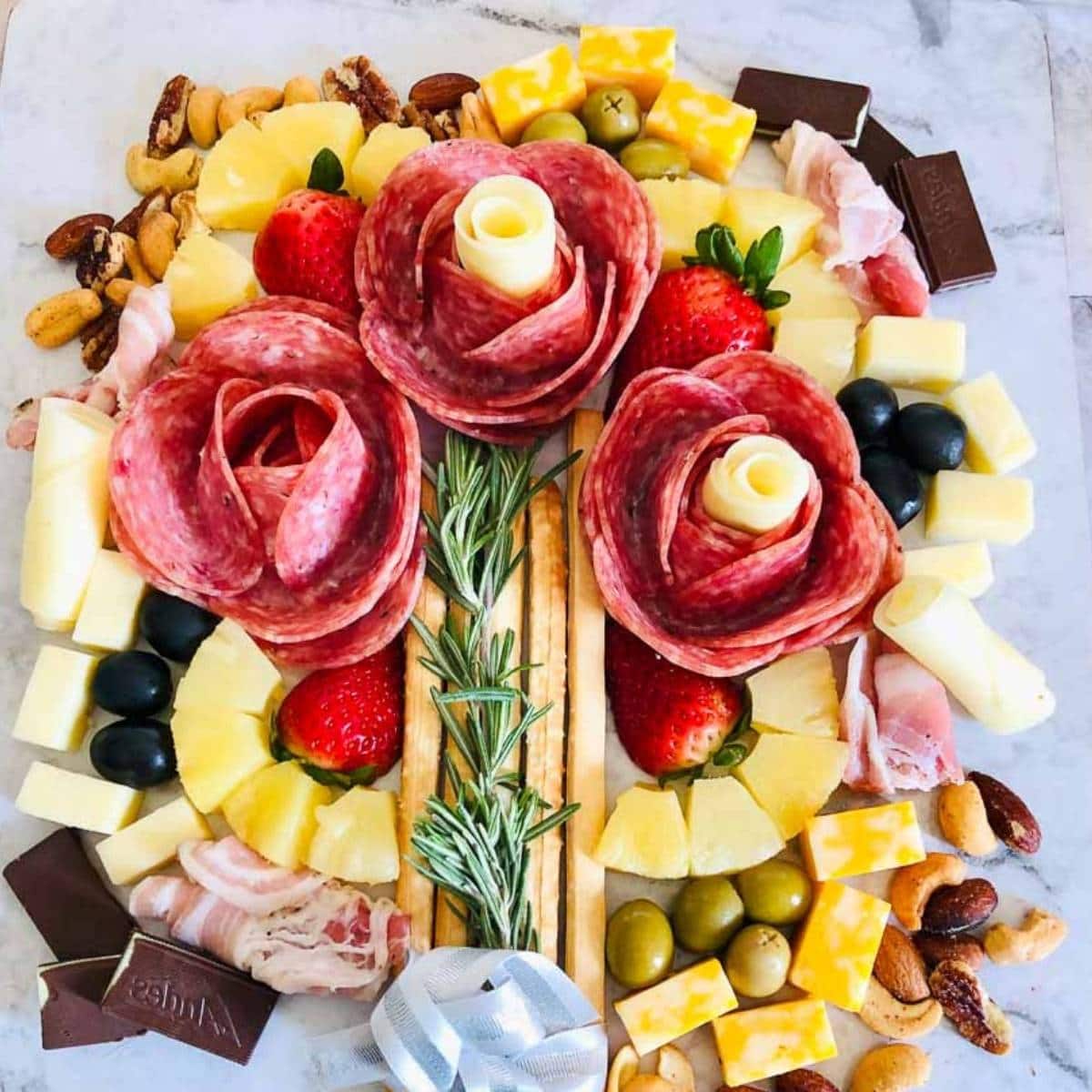 a charcuterie flower bouquet laying flat on the counter with cheese, crackers, and olives