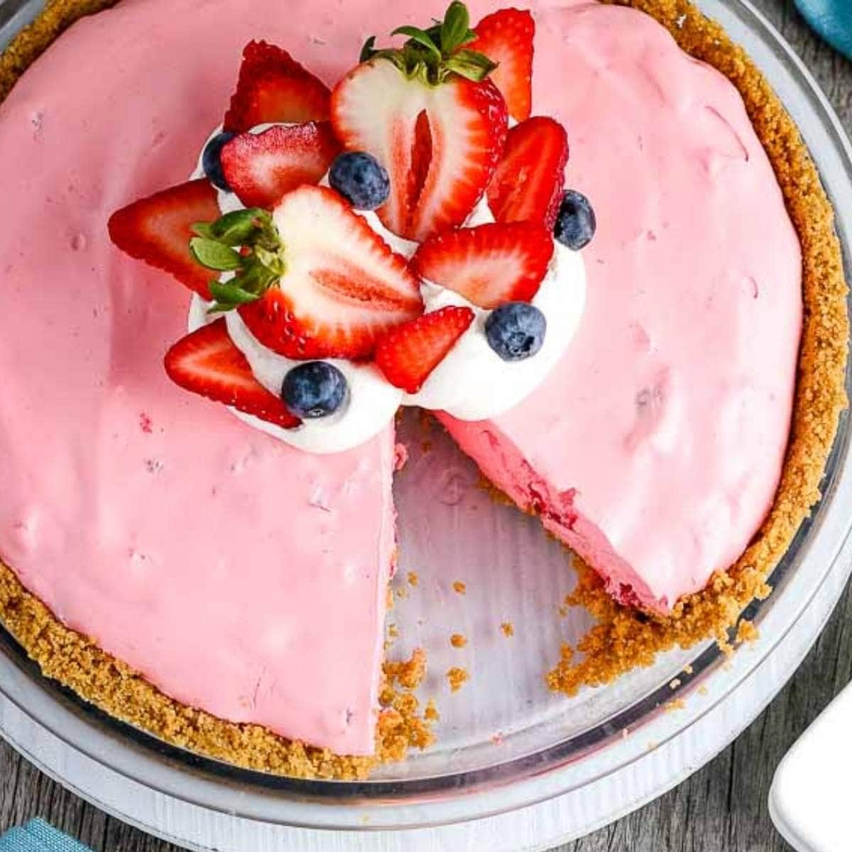 closeup of Strawberry Jello Pie garnished with fruit and whipped cream with a slice missing