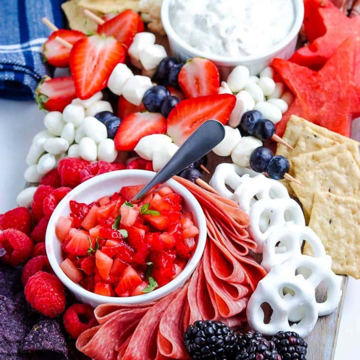patriotic snack board with berries, dips, and pretzels