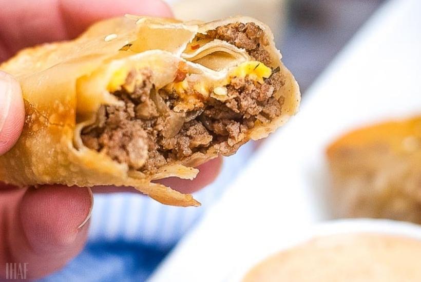 holding an air fryer cheeseburger egg roll with a bite taken out