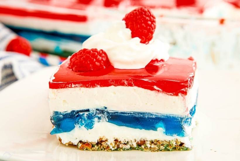 patriotic pretzel jello salad on a plate topped with raspberries and whipped cream