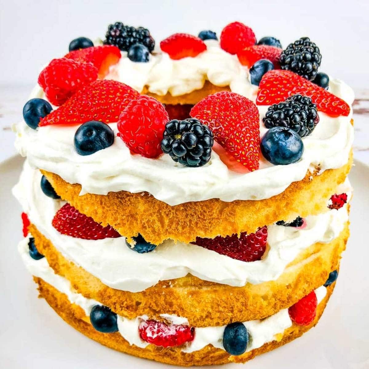 three layered angel food cake with berries and whipped cream