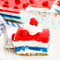 A square of red white and blue pretzel salad on a white plate with a fork.