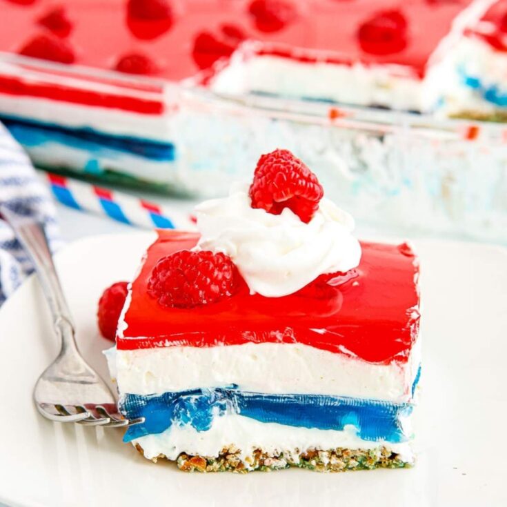 A square of red white and blue pretzel salad on a white plate with a fork.