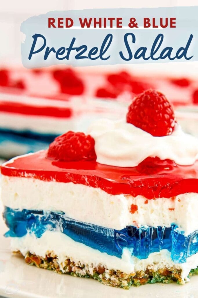 red white and blue pretzel salad topped with raspberries and whipped cream on a white plate
