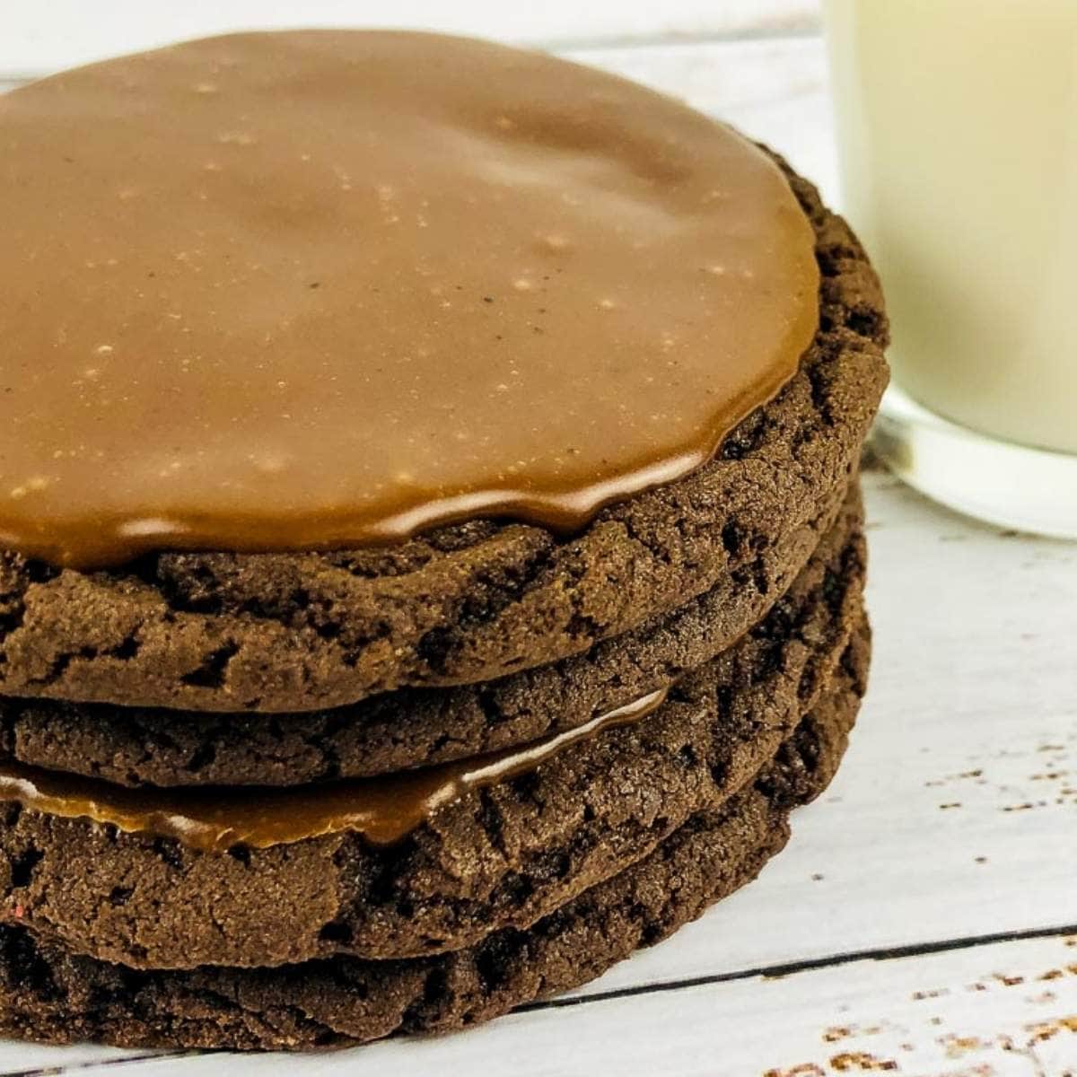 a stack of texas sheet cake cookies next to a glass of milk.