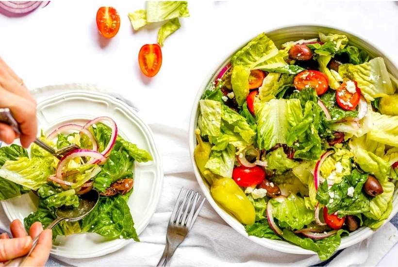 copycat panera greek salad in a bowl plus some on a plate next to forks