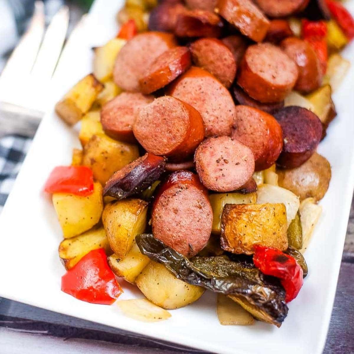 air fried smoked sausage, potatoes, peppers and onions on a white plate