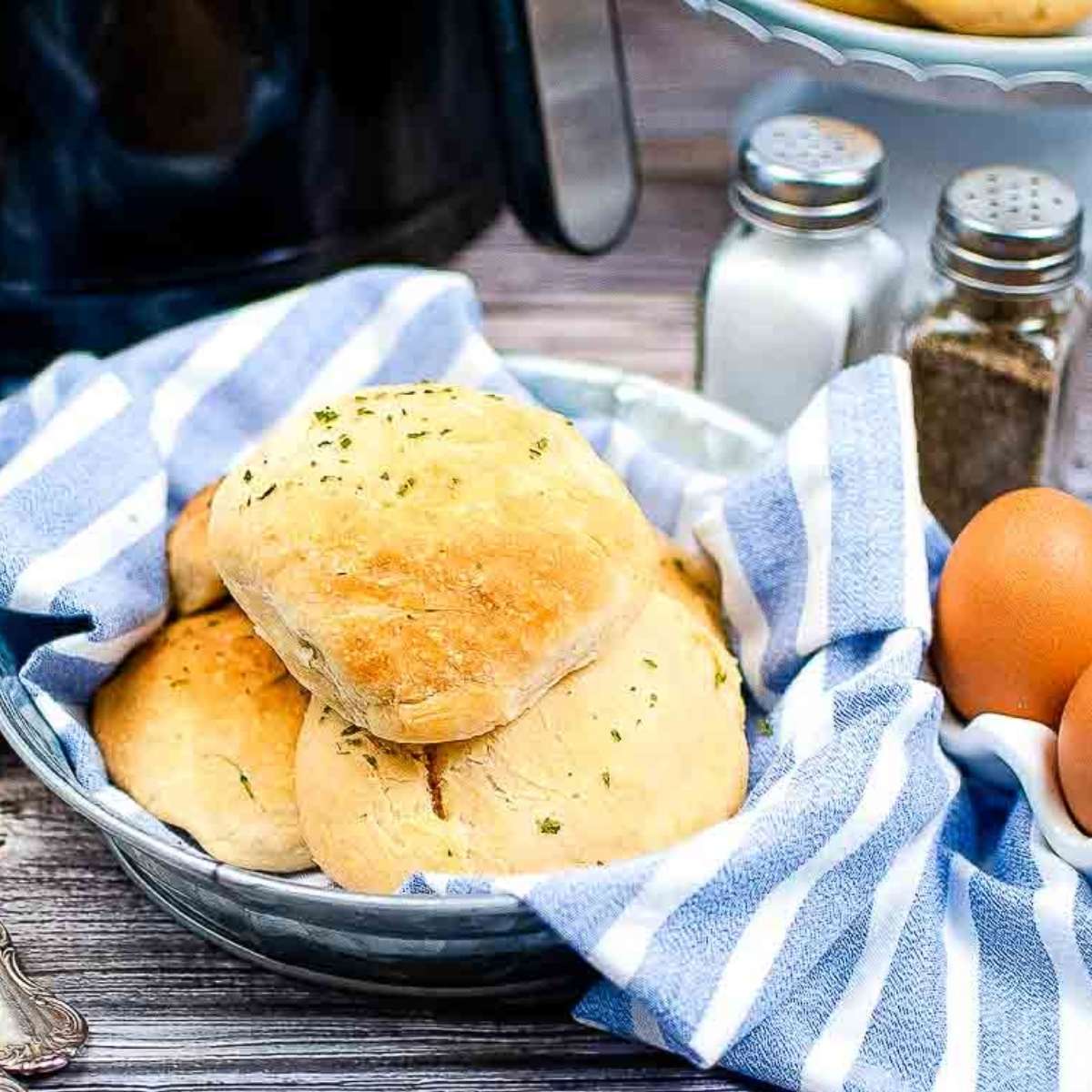 several air fryer breakfast bombs in a towel lined basket next to the air fryer