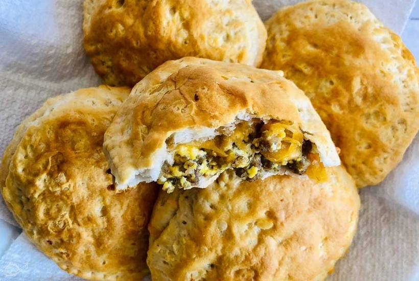 a stack of stuffed breakfast biscuits with one on top that has been cut open