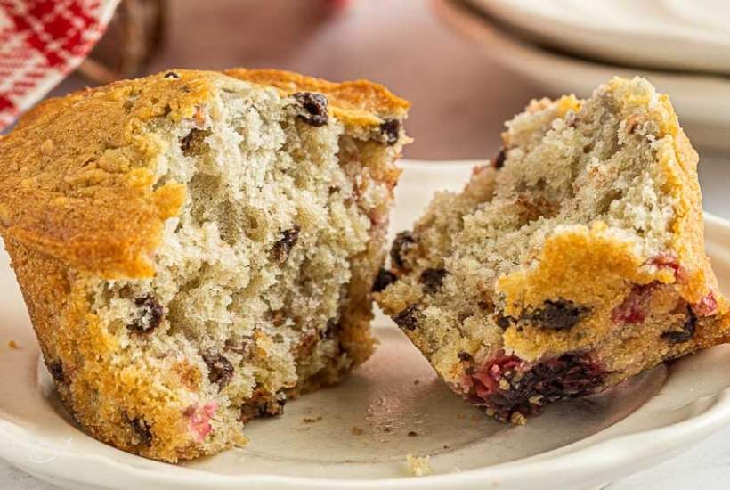 a raspberry oatmeal muffin cut in half on a white plate