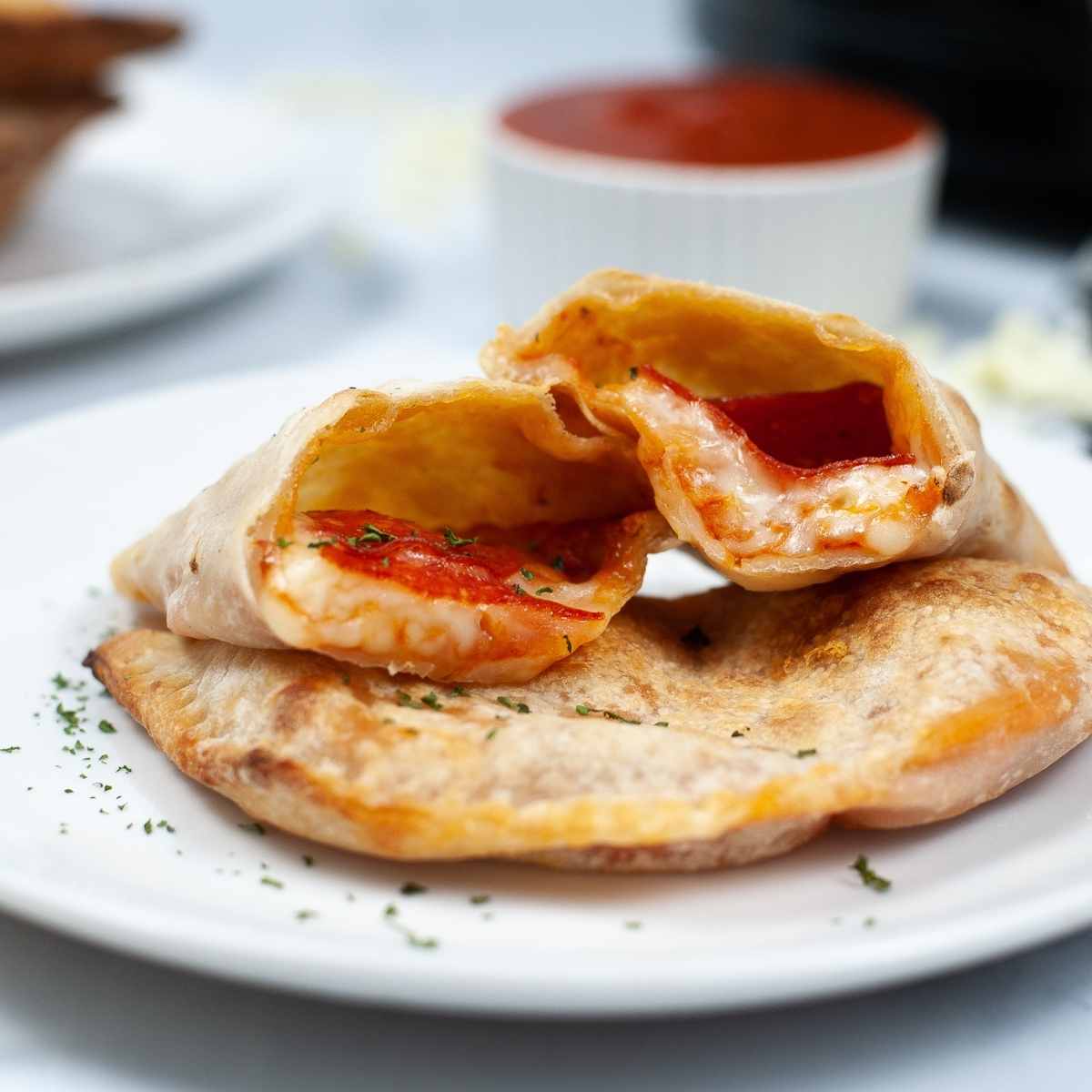 close up of cut air fried calzone on a white plate