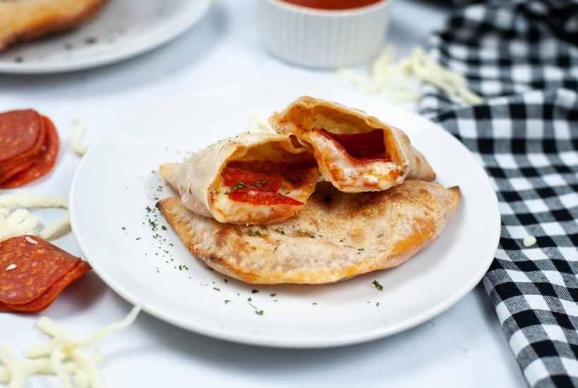 close up of a cut air fried calzone on a white plate