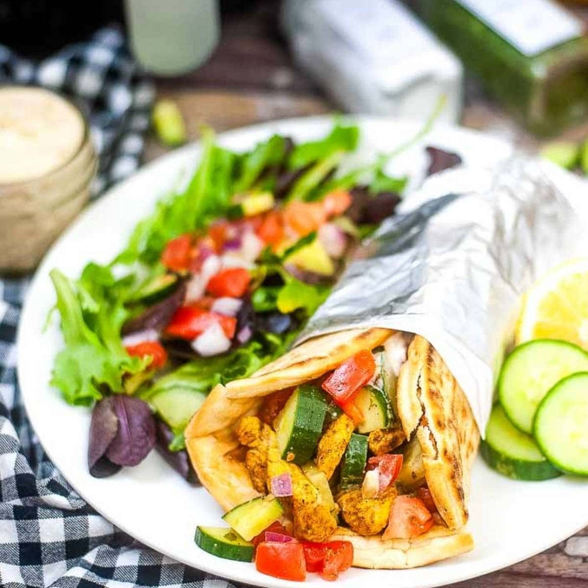 Air fried Chicken Shawarma wrap on a white plate with cucumber salad.