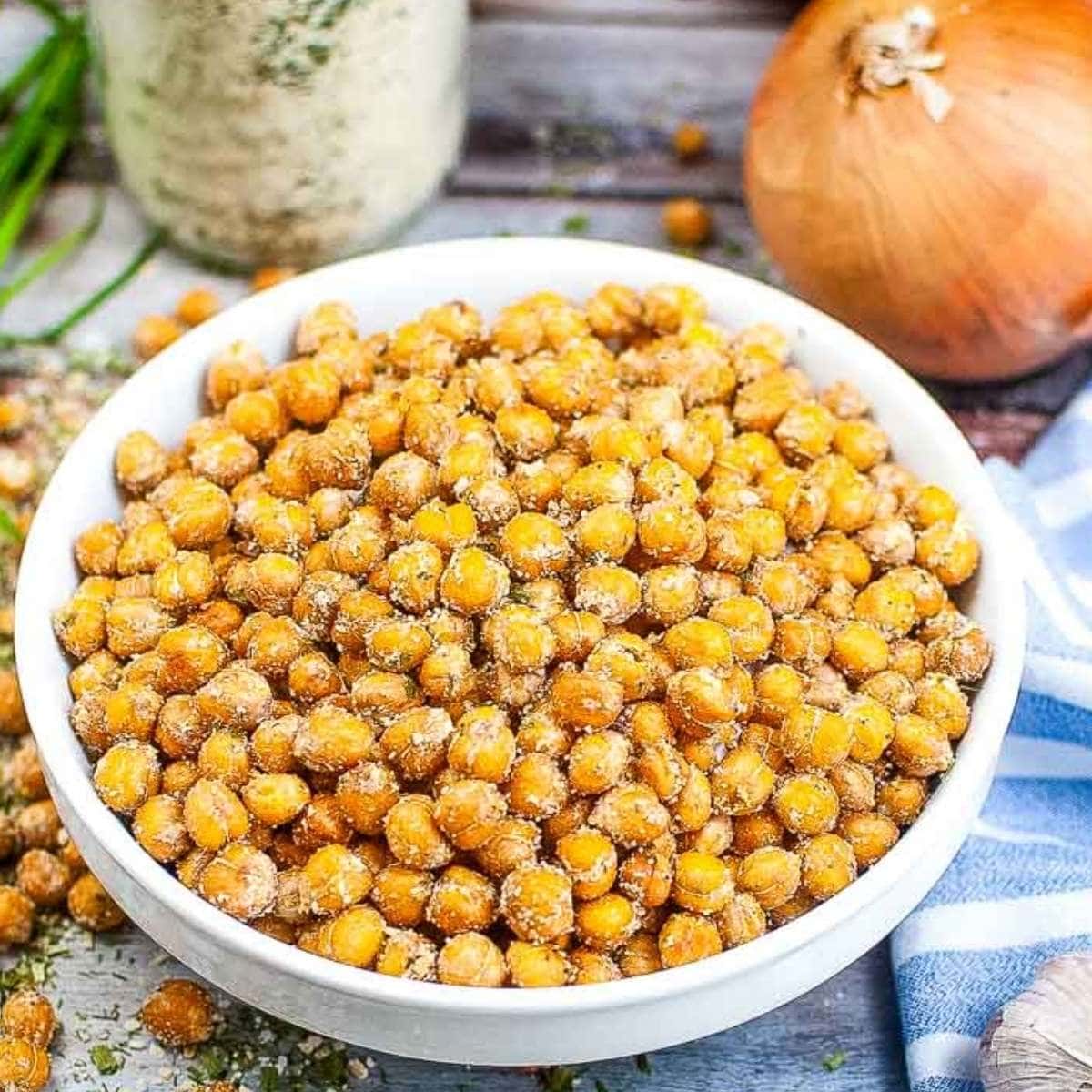 a bowl of air fryer ranch chickpeas next to seasonings and an onion.