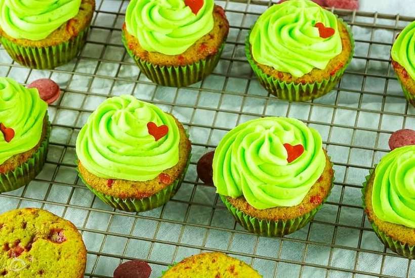 rows of Grinch cupcakes on a cooling rack.