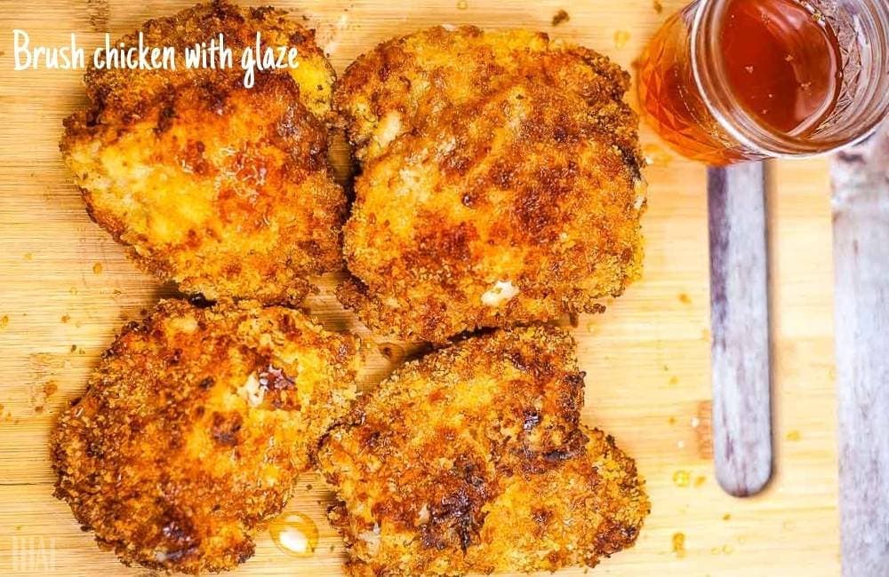 crispy air fried chicken thighs drizzled with honey glaze on a cutting board