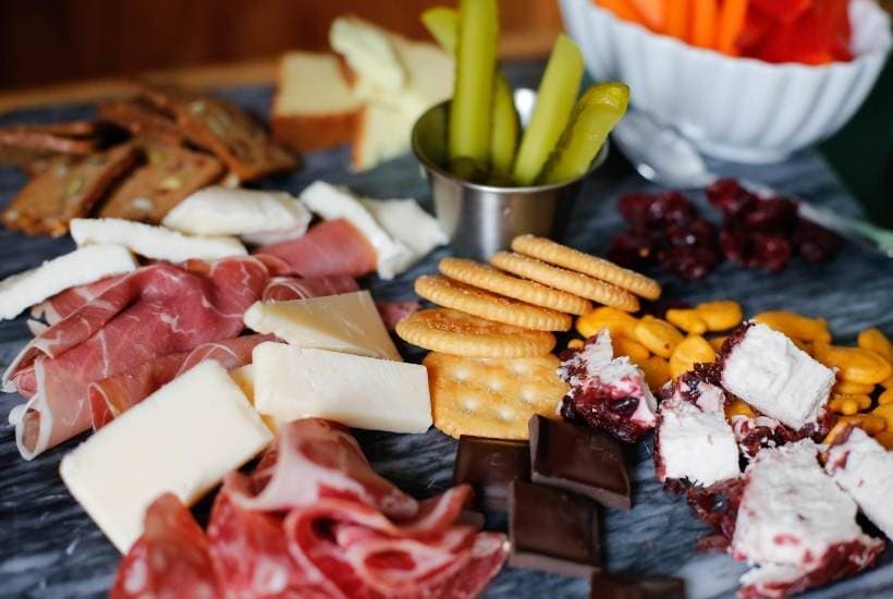 charcuterie board with meat, cheese, crackers, and veggies