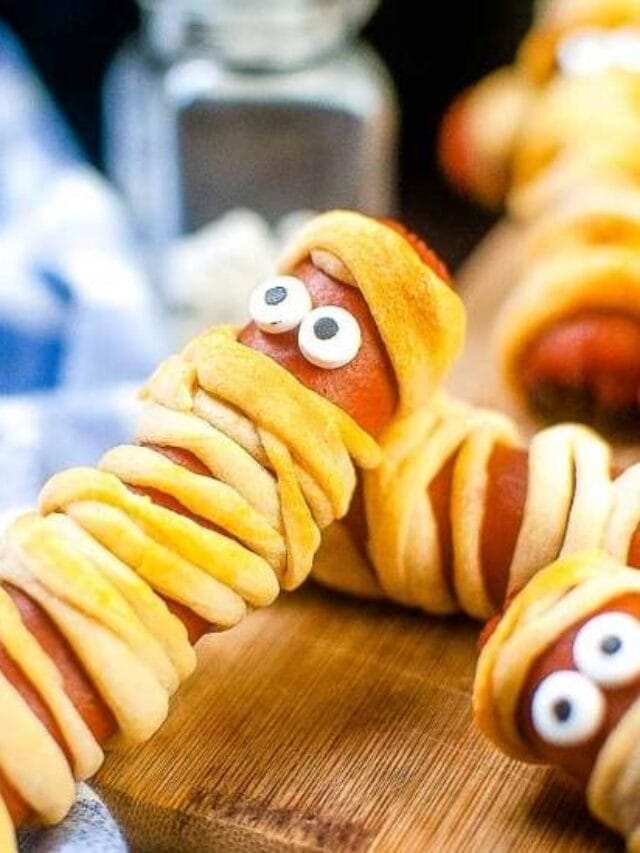 close up of a mummy dog laying on top of another with eyes next to a blue and white striped kitchen towel