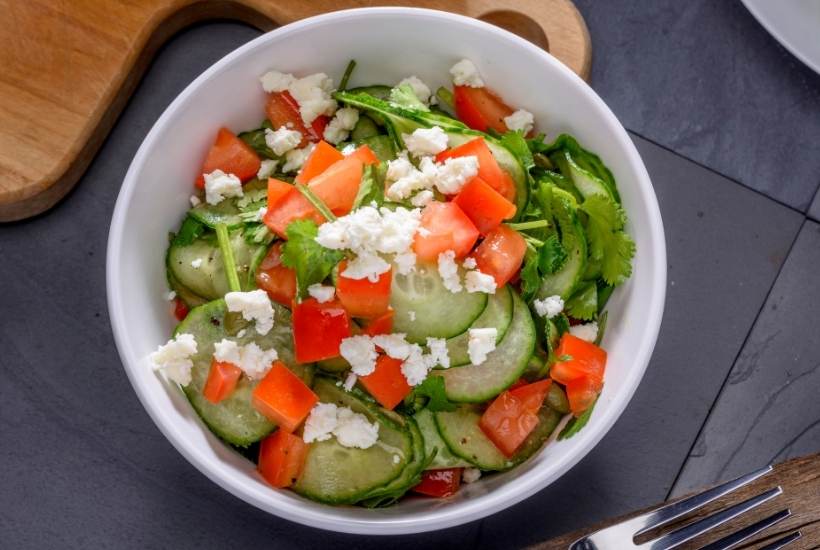 cucumber and tomato salad with feta cheese in a white bowl 