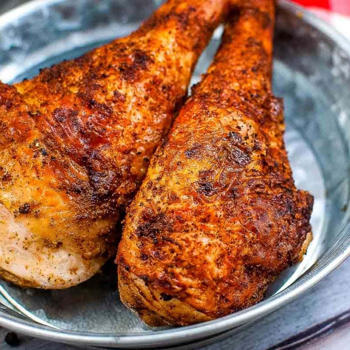 close up of two air fried turkey legs in a metal dish.