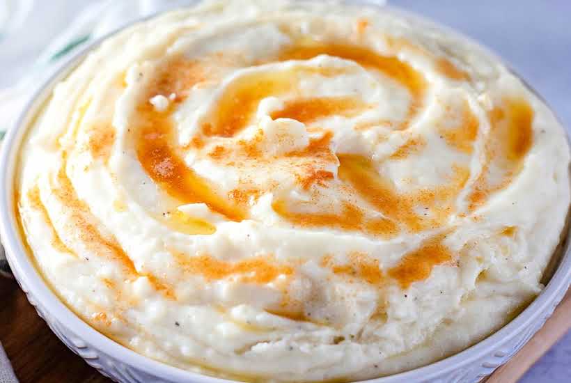 close up of Amish mashed potatoes in a white bowl topped with browned butter