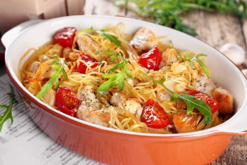 Casserole dish filled with chicken pasta with tomatoes.