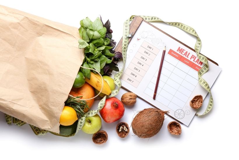 Grocery bag with food spilling out and meal planning chart.