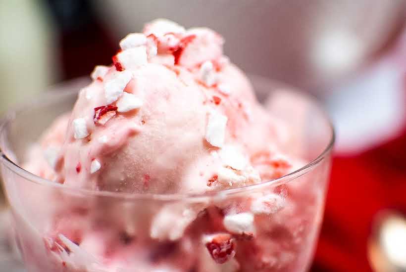 Close up view of ice cream in a clear glass cup topped with crush candy canes.