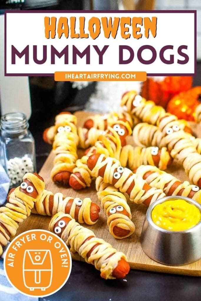 air fryer mummy dogs in a pile on a cutting board next to a container of mustard with text overlay.