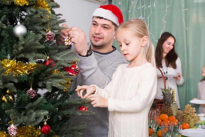 Dad and daughter hanging ornaments on the Christmas tree.