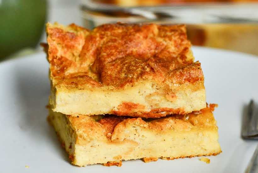 two slices of old fashioned bread pudding stacked on top of each other on a white plate.