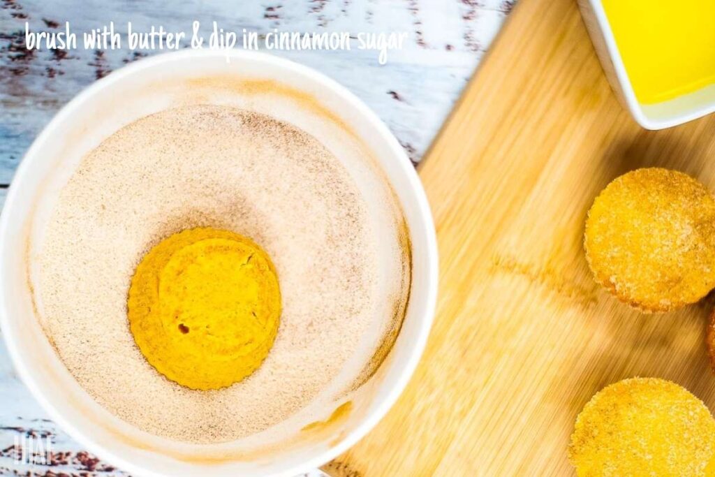 pumpkin muffins being dipped into cinnamon sugar topping.