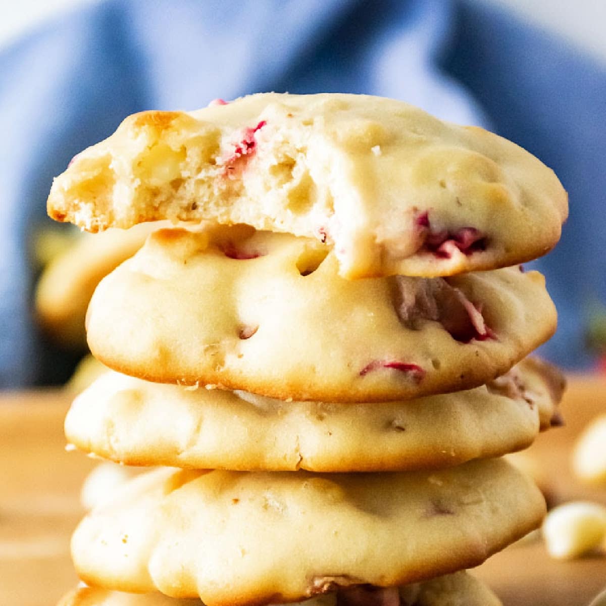 Front close up view of a stack of strawberry cheesecake cookies with top one with a bite taken out of it.