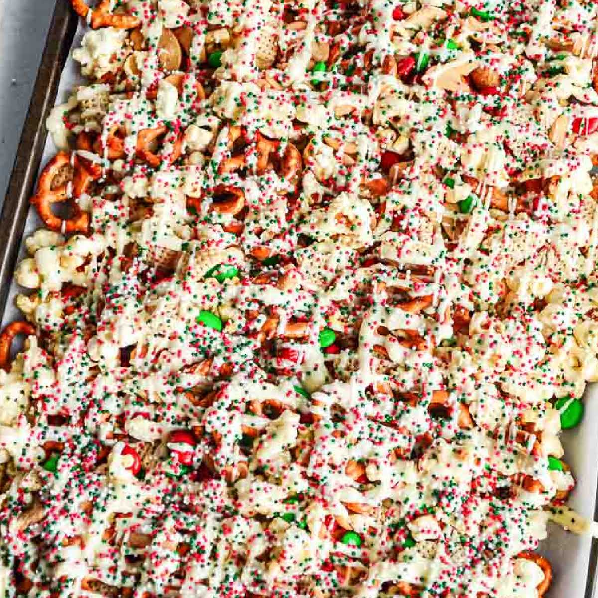 Christmas crunch Chex mix on a parchment paper lined baking sheet.