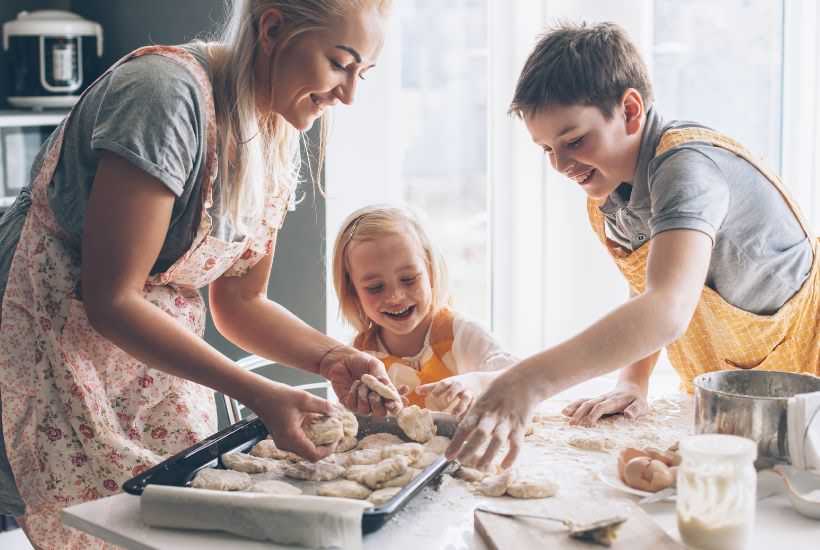 Two kids helping their mom cook dinner.