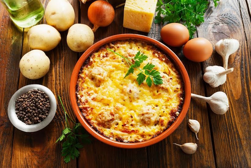 A bowl of food made with pantry items next to potatoes, eggs, and garlic.